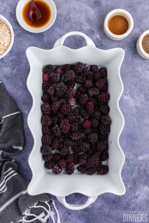 Blackberries in the bottom of a white baking dish.