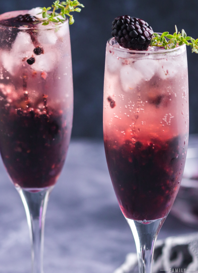 photo of two champagne glasses filled with blackberry cocktail that's dark purple on bottom and lighter pink on top.