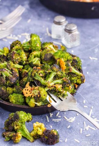 cast iron pan piled high with roasted broccoli, fork scooping broccoli