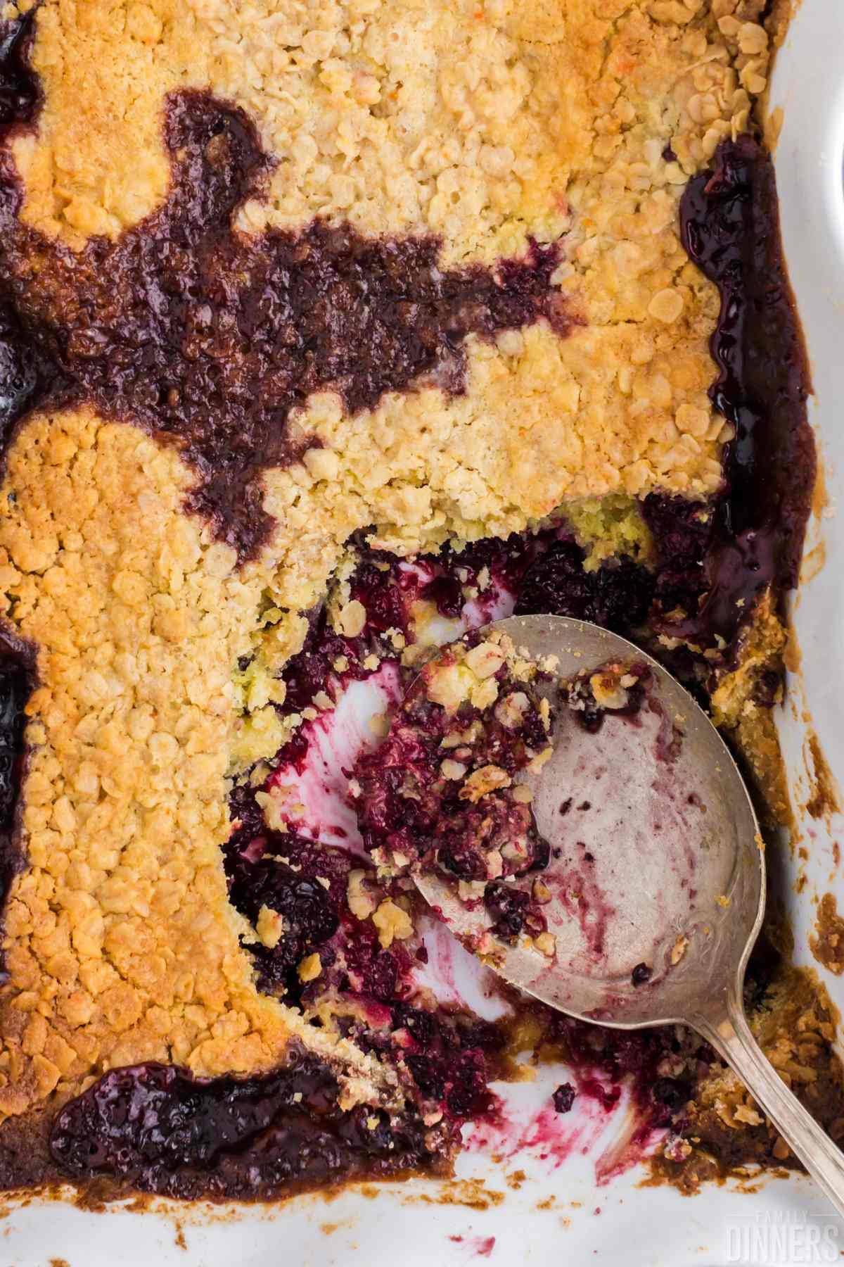 Blackberry dump cake in a casserole dish with a scoop taken out.