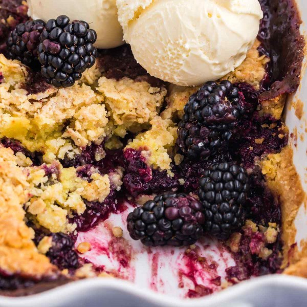 Fresh blackberry dump cake with ice cream scoops in a baking dish.
