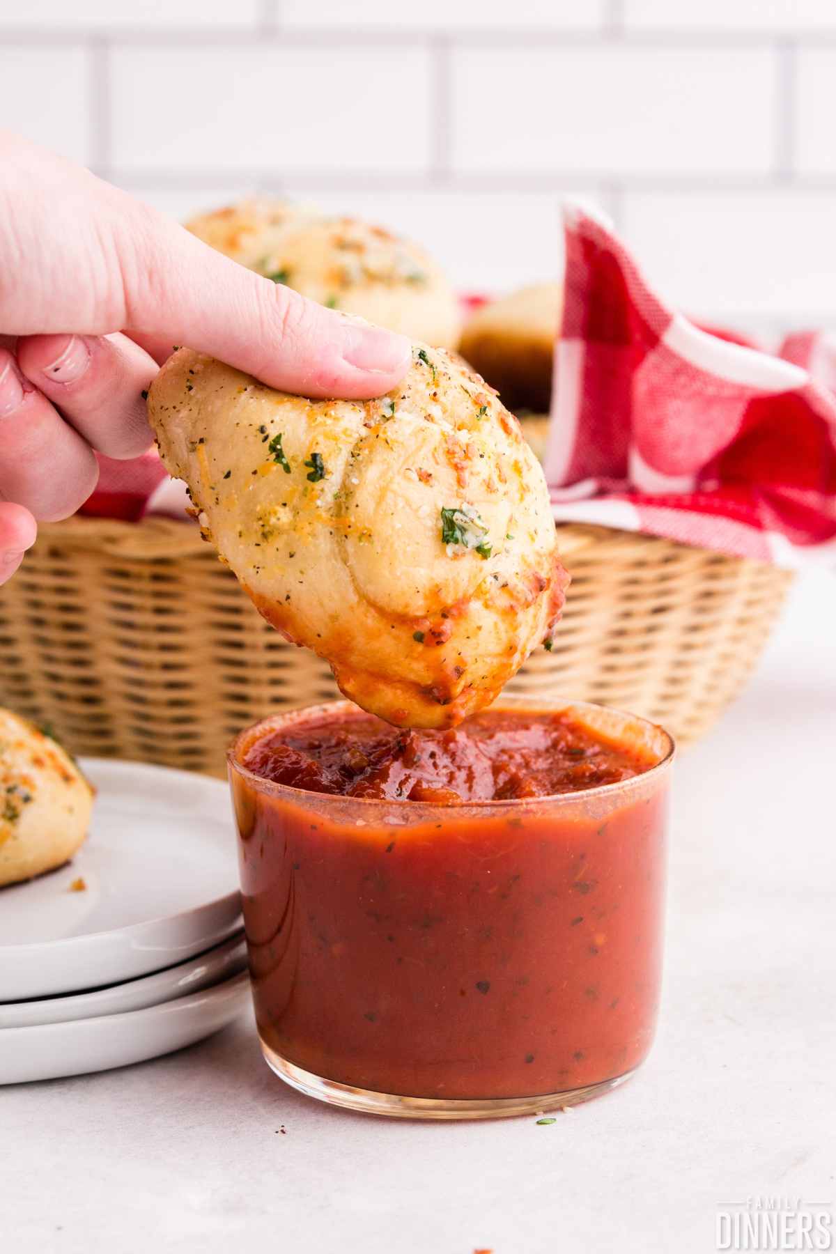 Garlic knot dipped into marinara sauce.