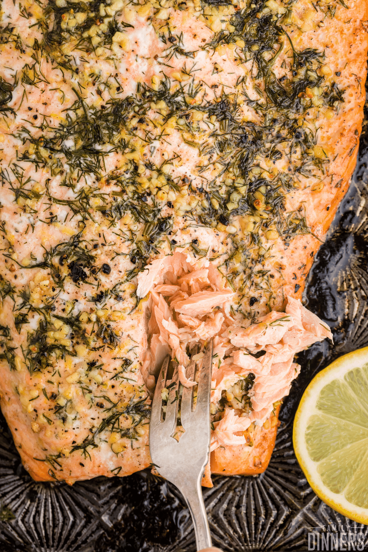 baked salmon with lemon dill butter being flaked with a fork