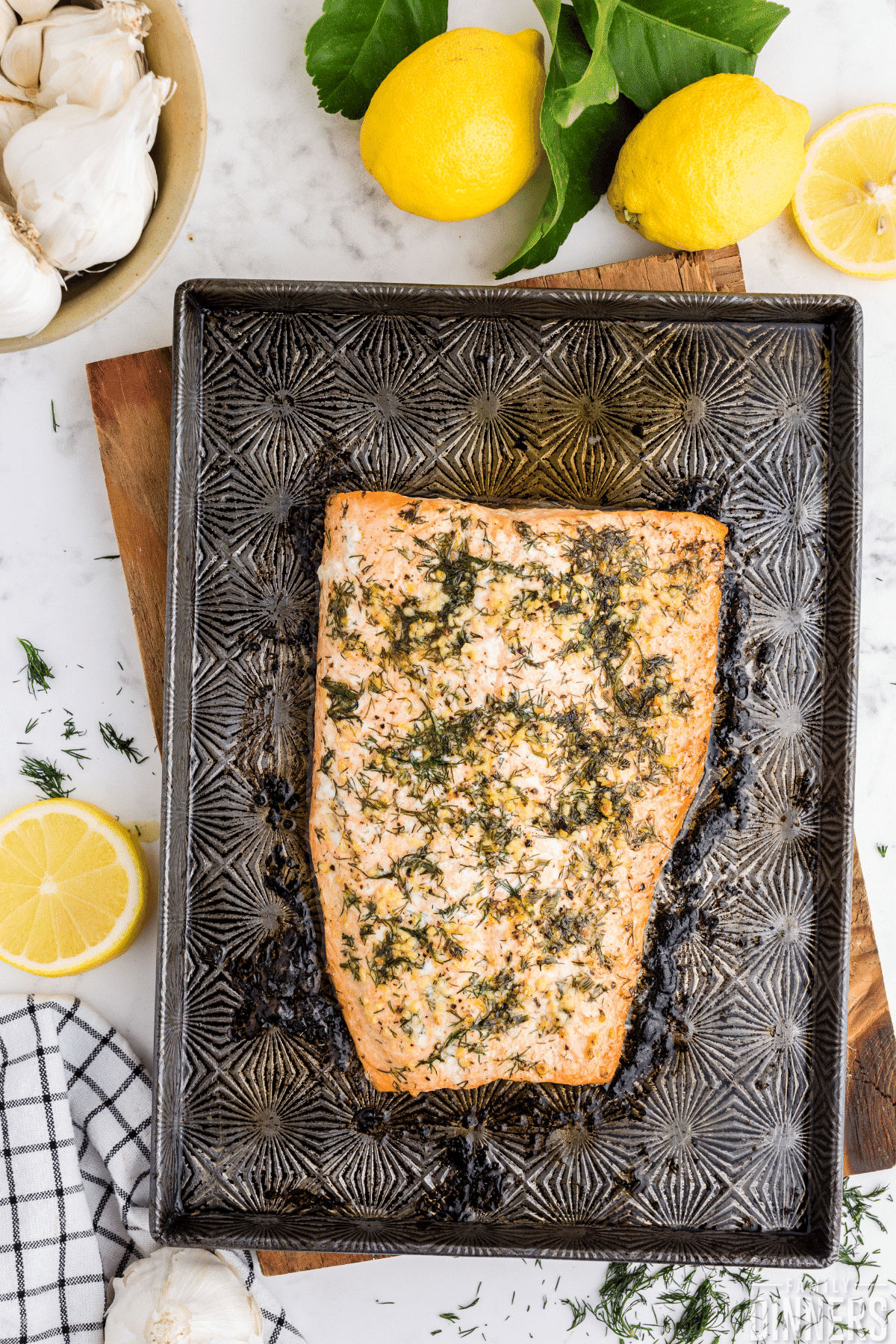 oven baked salmon with dill salmon seasoning on decorative baking sheet on marble counter