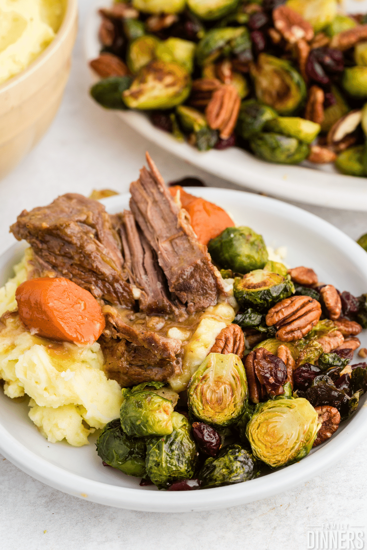 pot roast on a bed of mashed potatoes, carrots and brussels sprouts