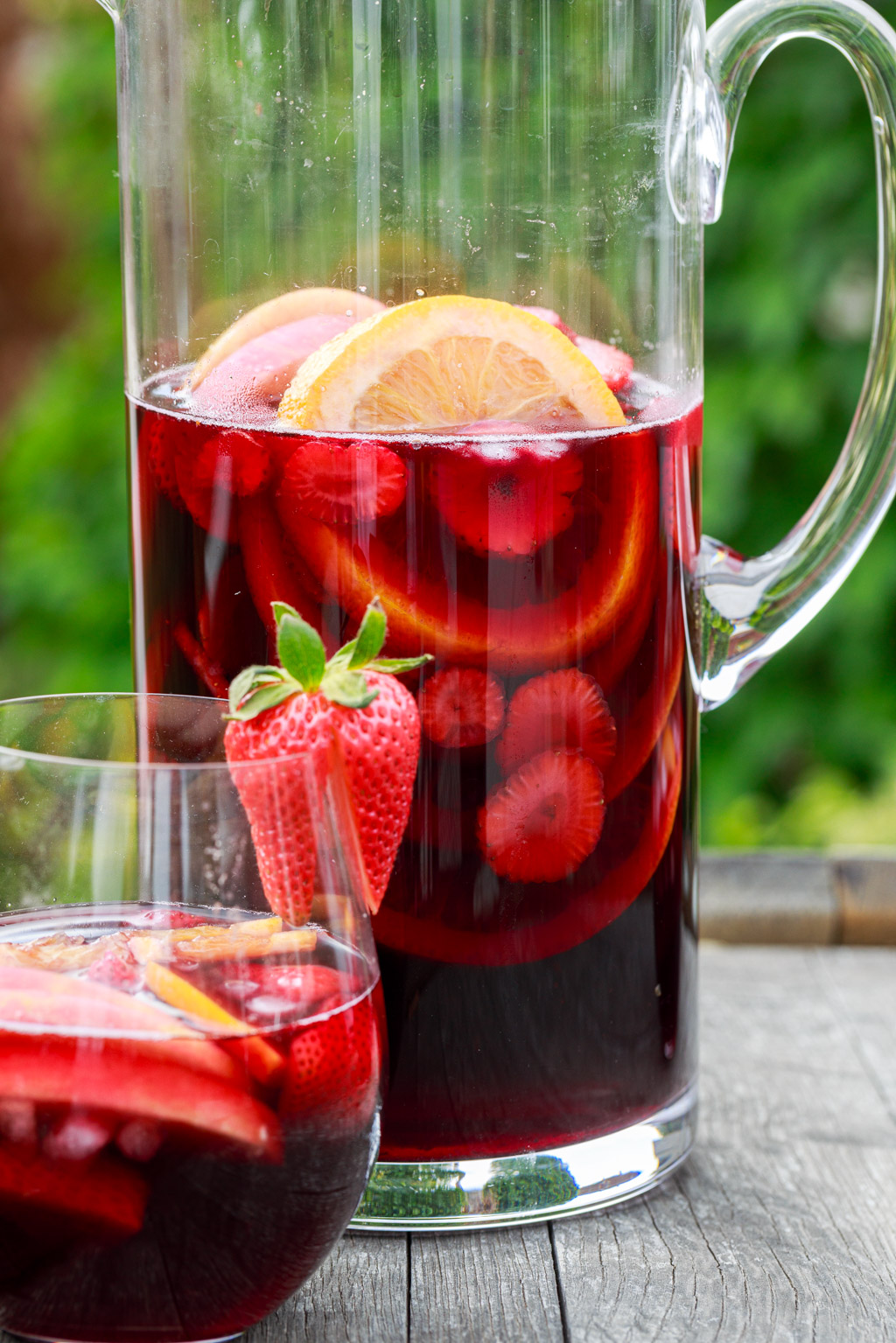 red wine sangria in a pitcher and stemless wine glass.