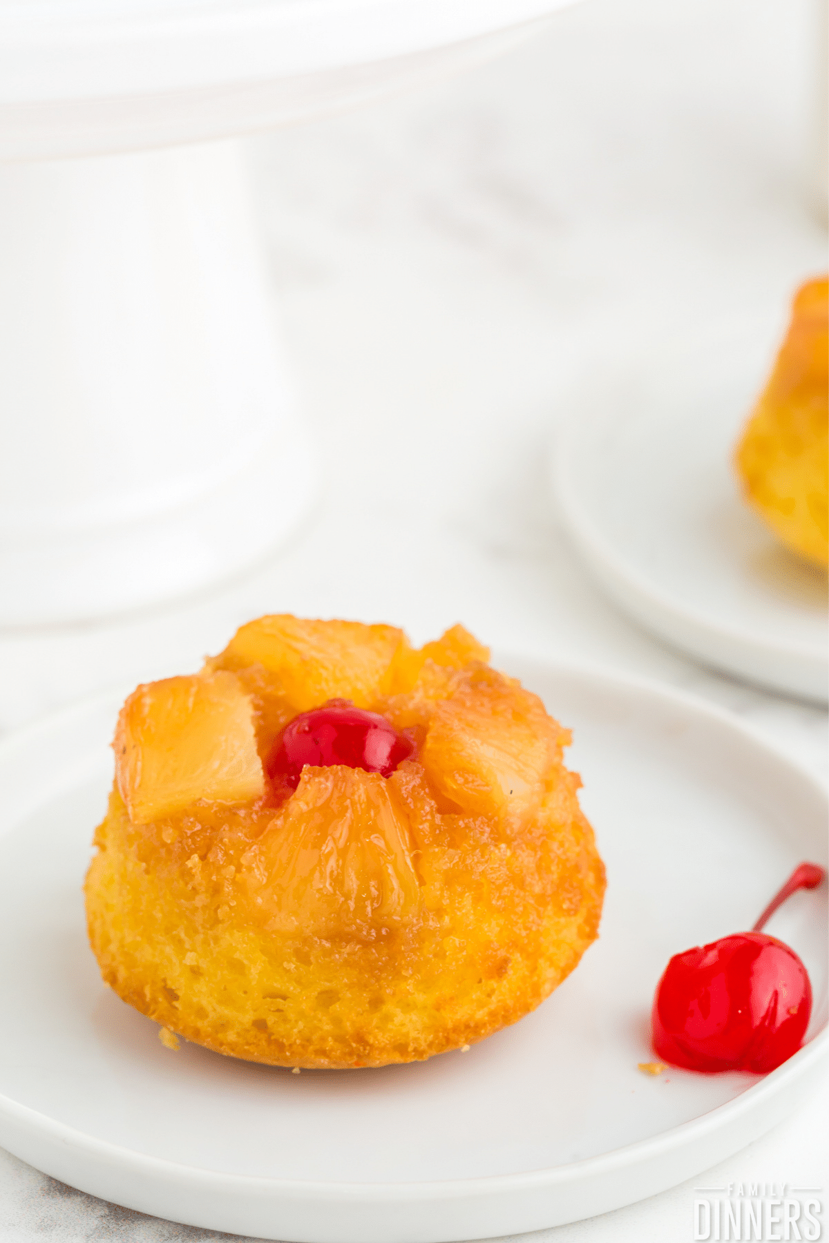 mini pineapple upside down cake on a white plate with a red cherry