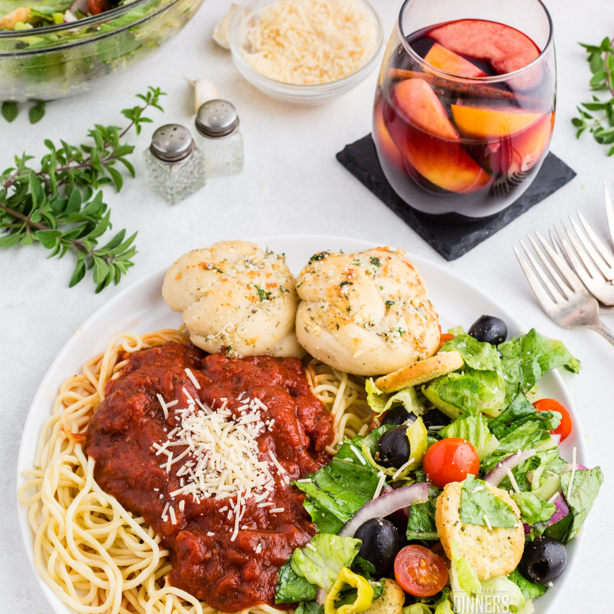 plate full of spaghetti with marinara sauce, salad and garlic knots