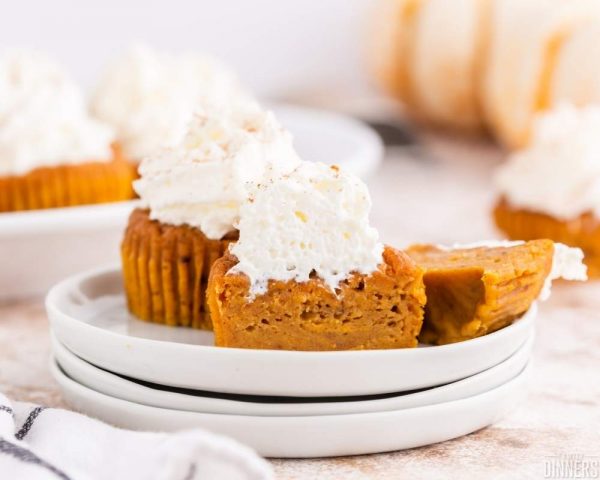 recommended recipe pumpkin pie cupcakes. Image of stack of 3 round plates with 3 sliced pumpkin pie cupcakes on top with whipped cream on top of cupcake