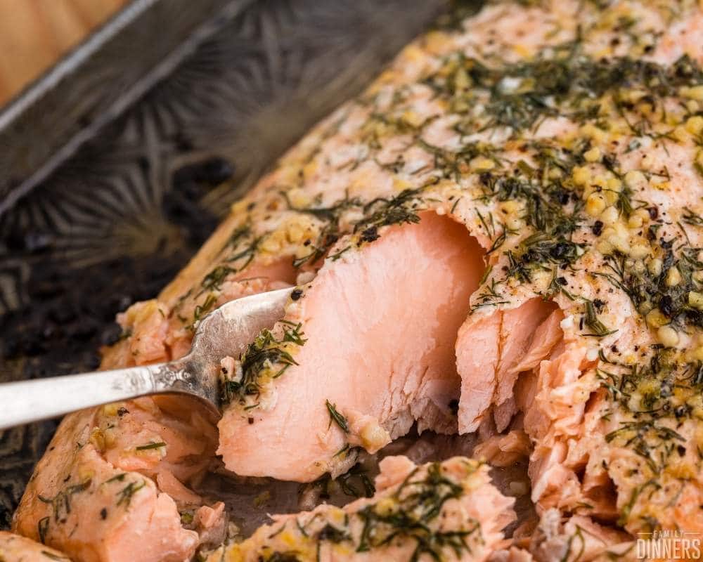recommended recipe: baked salmon with lemon - image of salmon being flaked with a fork on a black dish