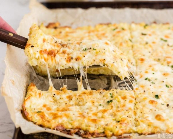 recommended recipe: cheesy cauliflower breadsticks. Image: tray of slicked cheesy cauliflower breadsticks being pulled out of the pan