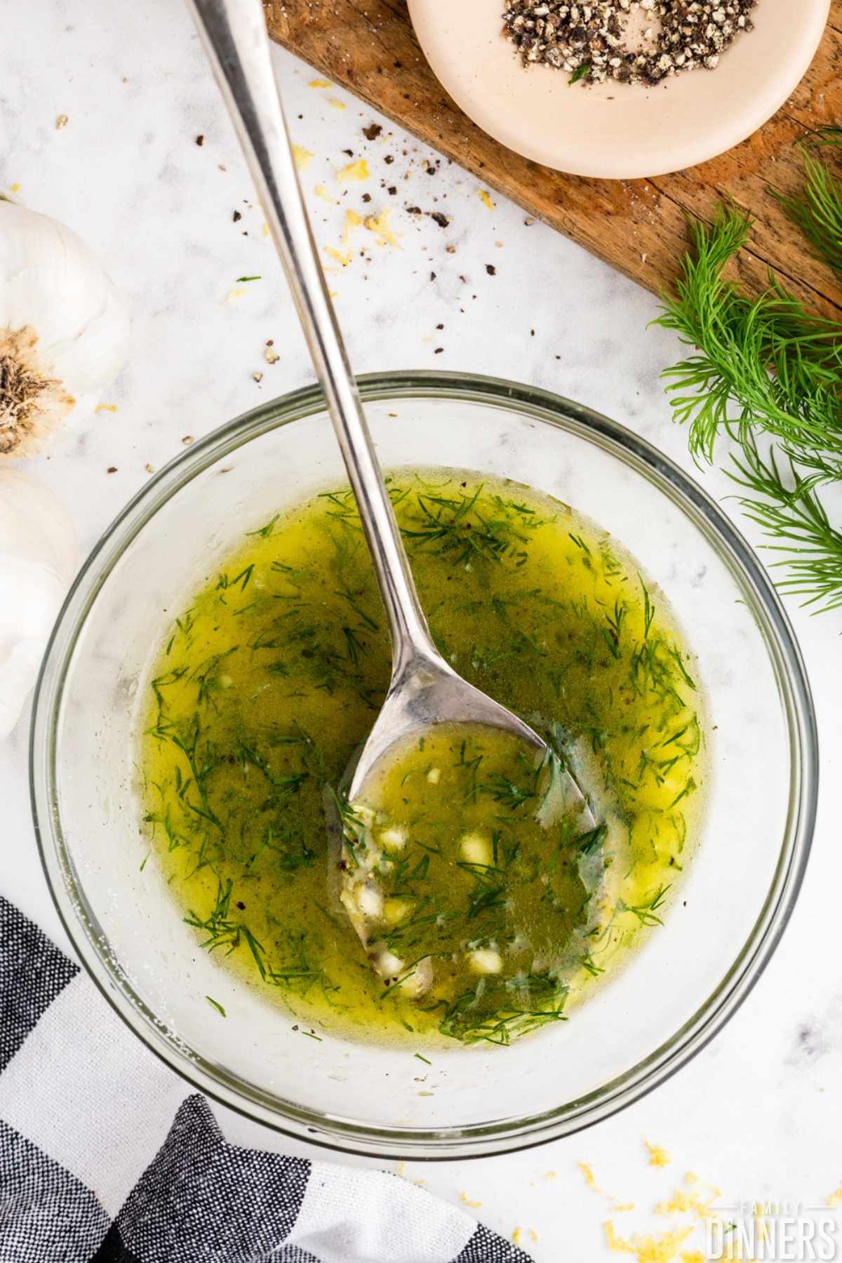 Lemon dill marinade in a glass bowl with a large silver spoon