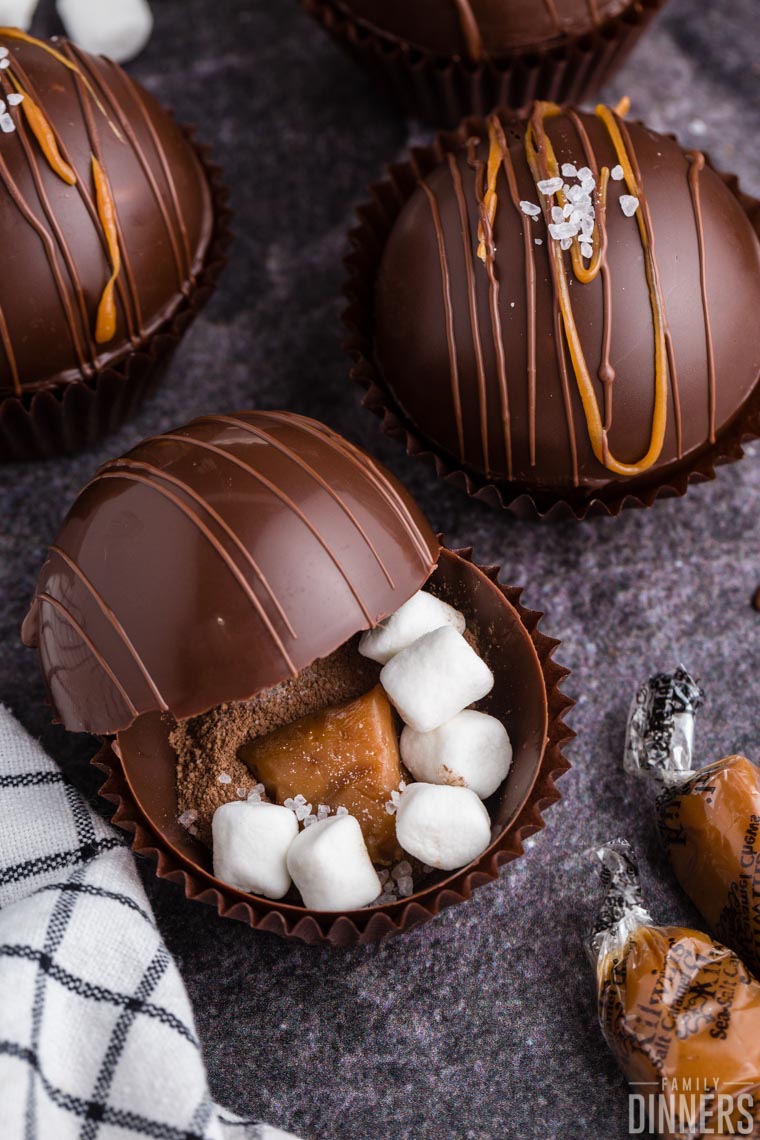 DIY hot chocolate bombs with salted caramel displayed on a dark gray counter