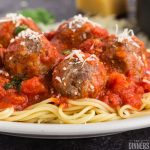 spaghetti and meatballs with parmesan cheese sprinkled on top piled on a white plate