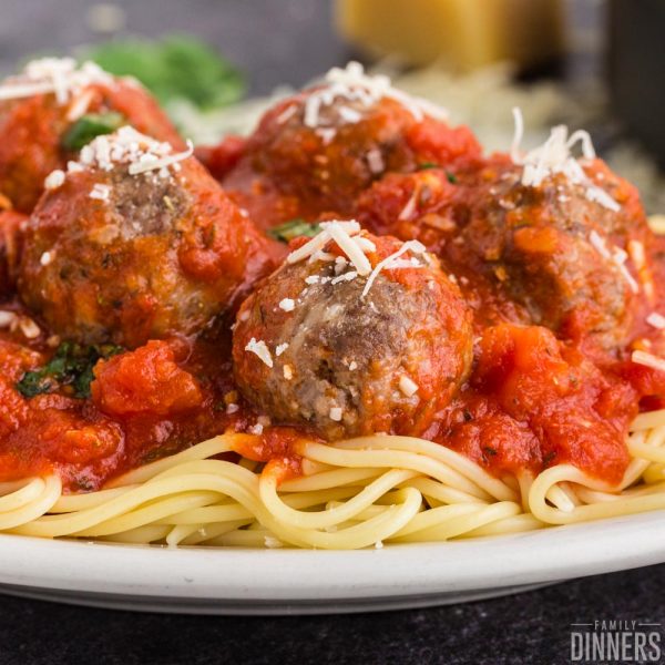 spaghetti and meatballs with parmesan cheese sprinkled on top piled on a white plate