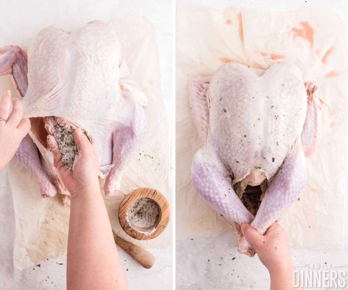 hand putting spices in the raw turkey between skin and breast