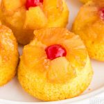 pineapple upside down mini cakes on a white plate. Red cherry on top.