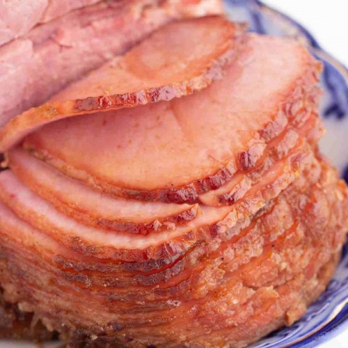 Juicey, sliced ham on a blue and white serving plate