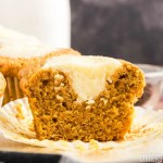 cream cheese pumpkin muffin sliced in half to show the delicious pumpkin filling.