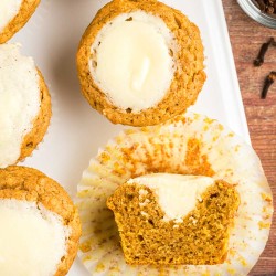 pumpkin cream cheese muffins on a platter, one cut in half