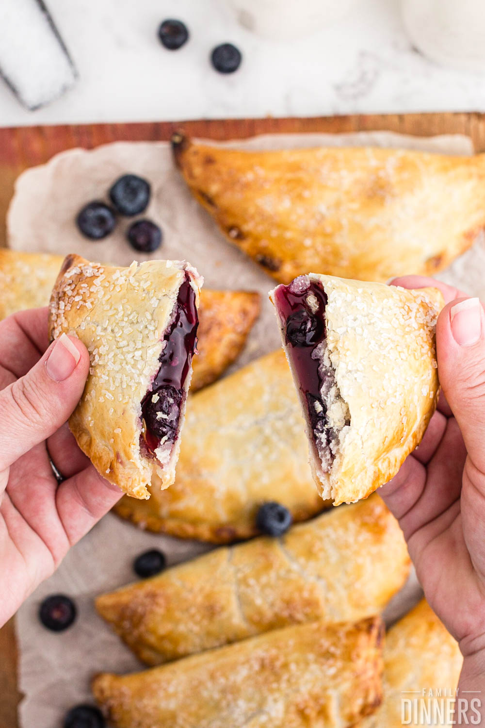 hands holding opened blueberry hand pie