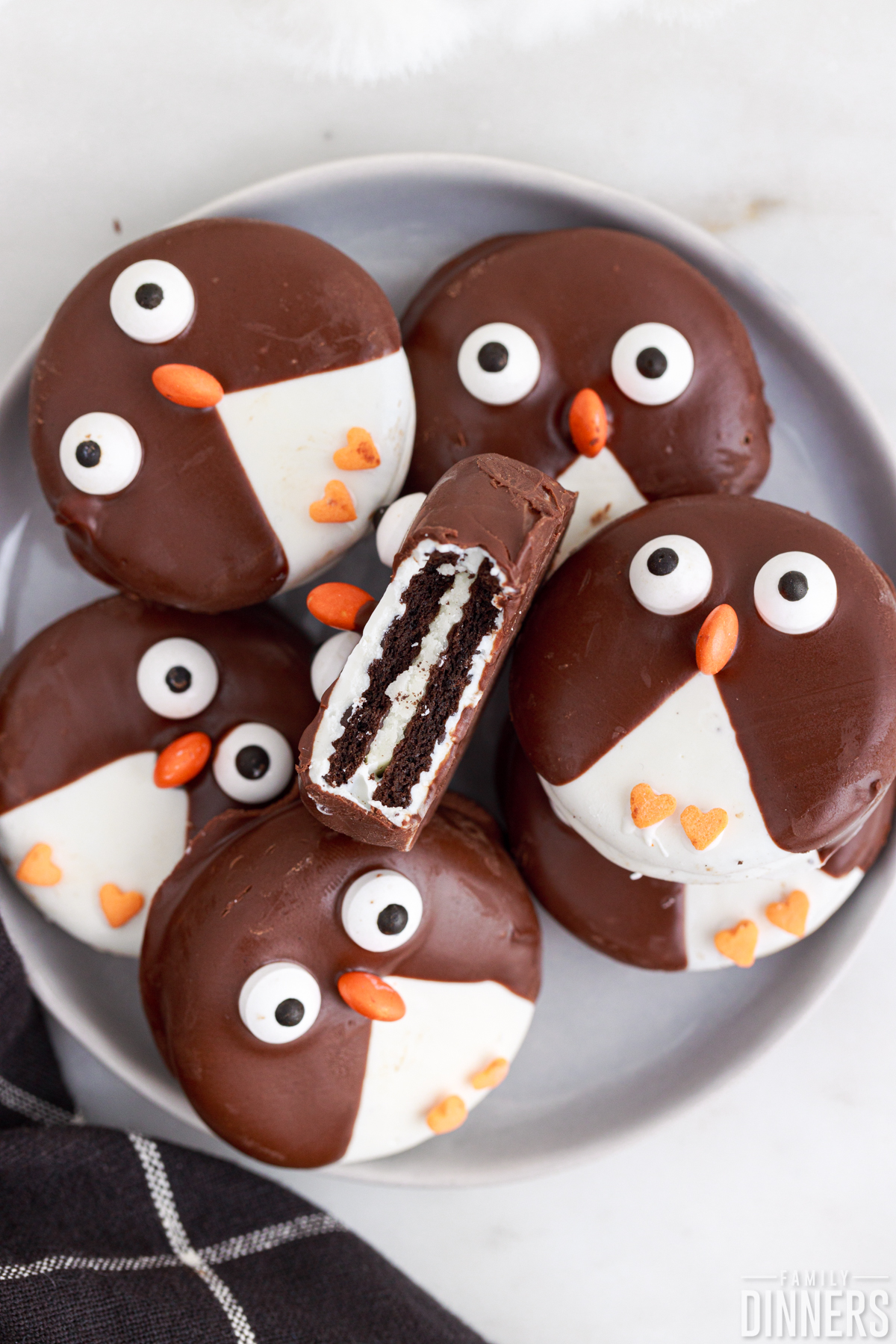 plate of penguin cookies. Top cookie facing up has bit out of it.