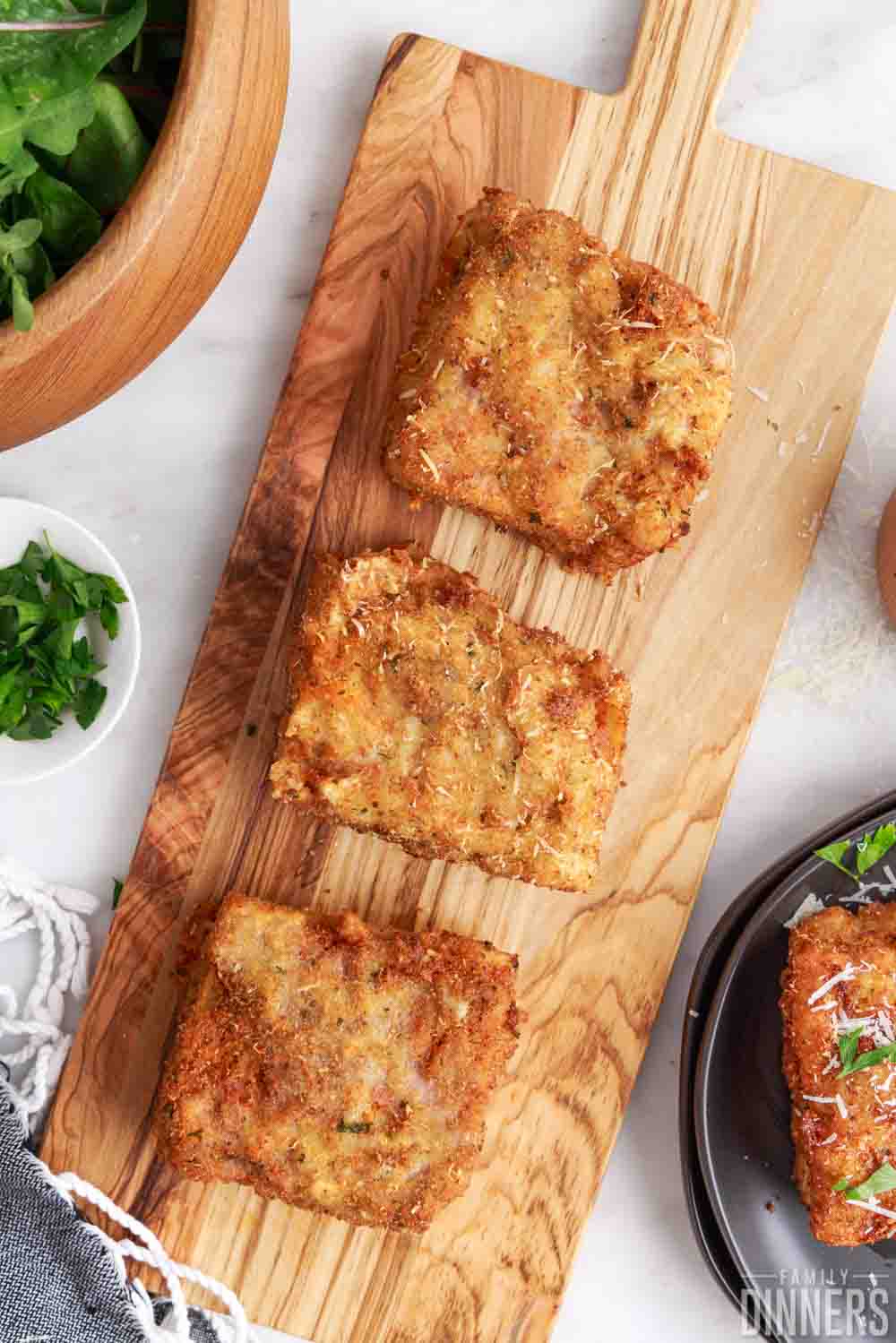 3 pieces of deep fried lasagna on a wood tray