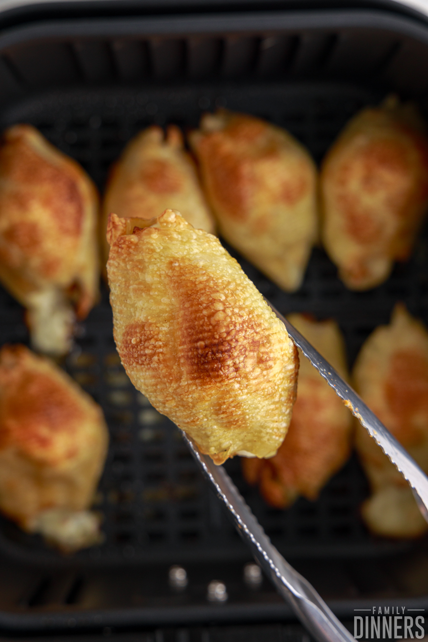 tongs holding up chipotle chicken stuffed pasta