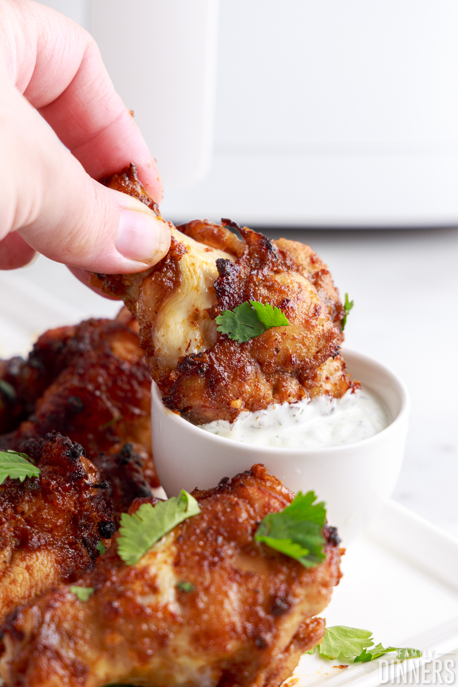 dipping an air fried chicken wing into cilantro sour cream sauce
