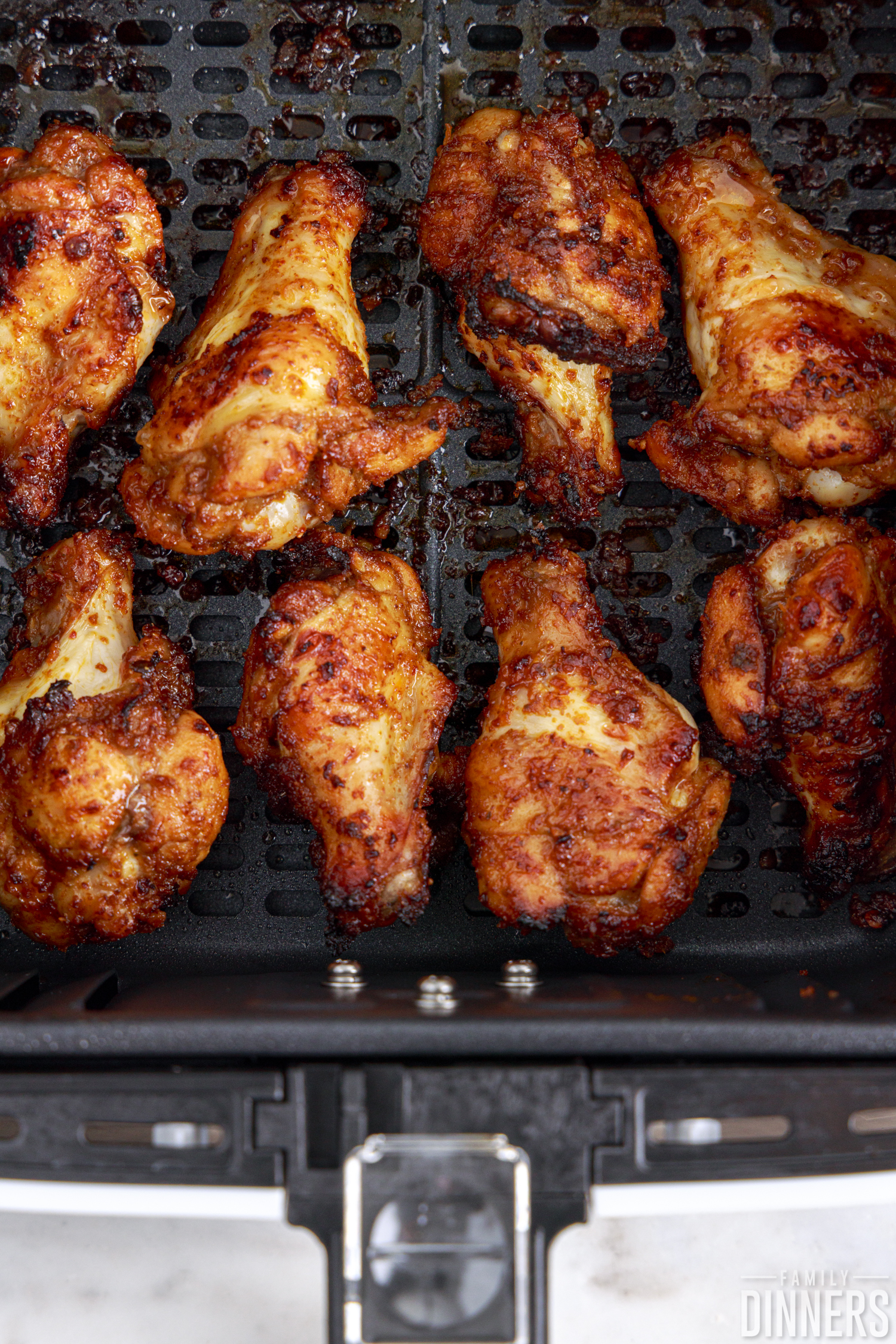 chicken wings sitting in the air fryer basket after cooking