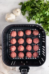 Raw meatballs in an air fryer.
