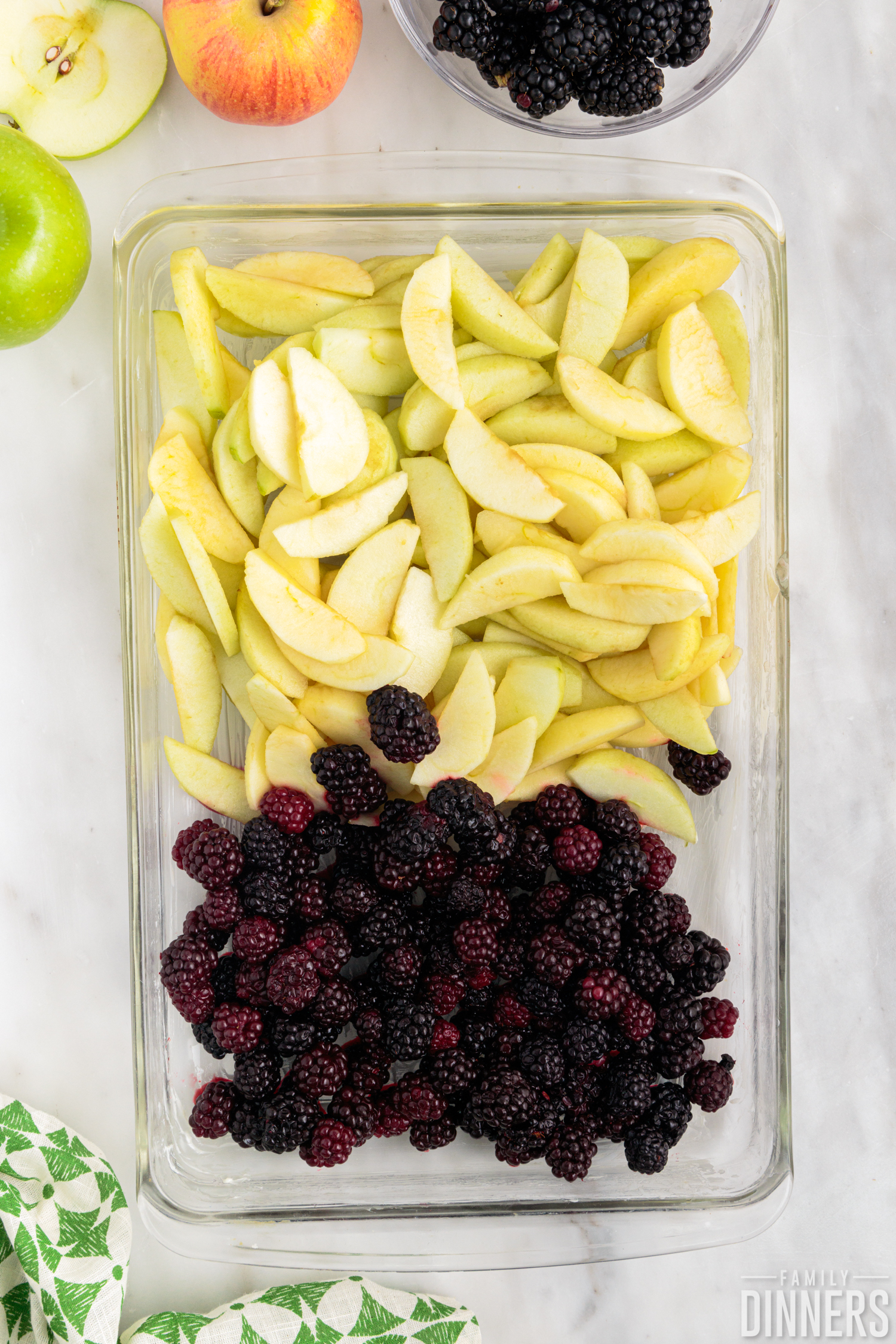 blackberries and sliced apples arranged in a rectangular glass baking dish,