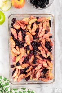 filling ingredients, sliced apples and blackberries all mixed together in a glass rectangular baking dish.