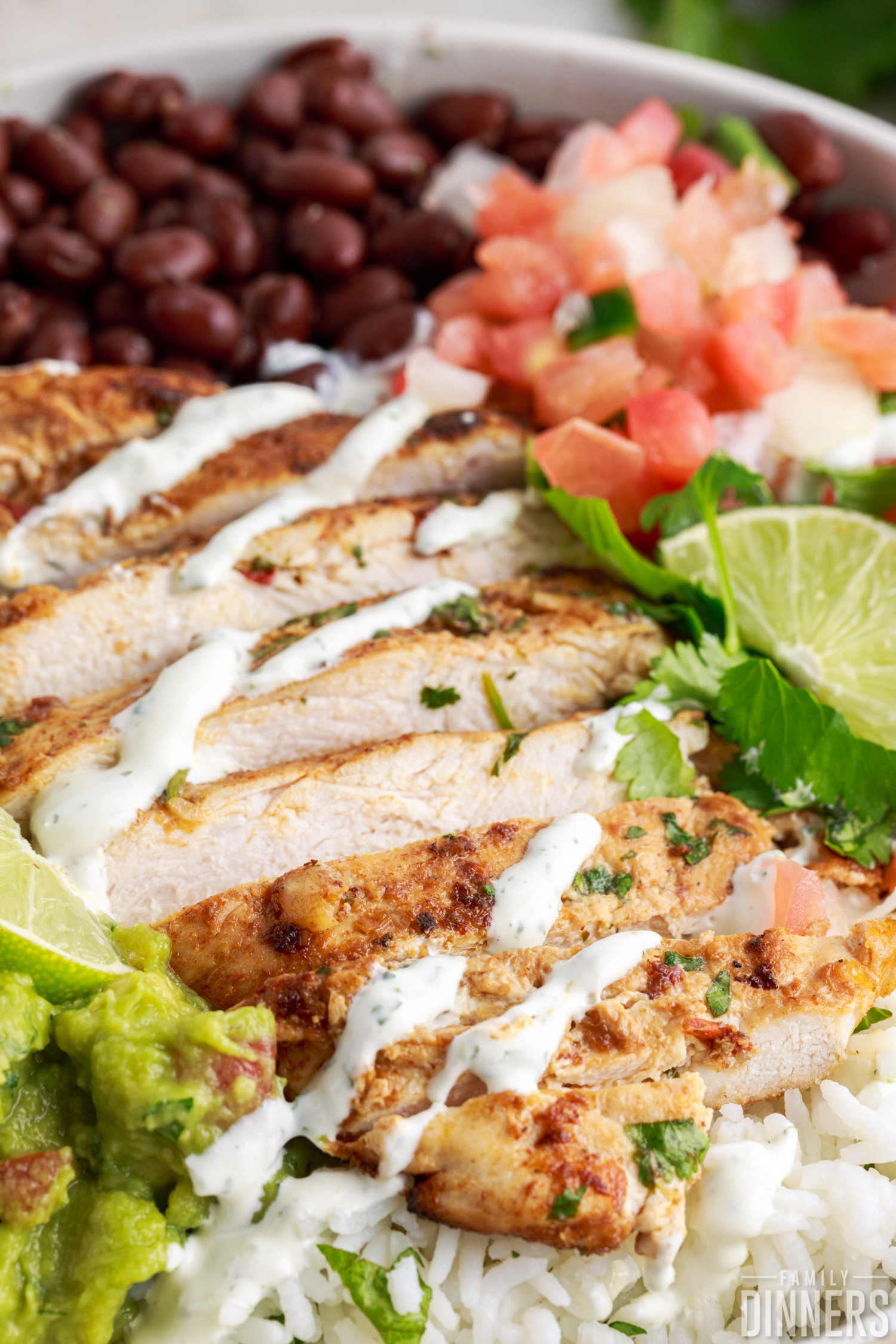 close up of chicken burrito bowl with black beans and pico and sour cream drizzle