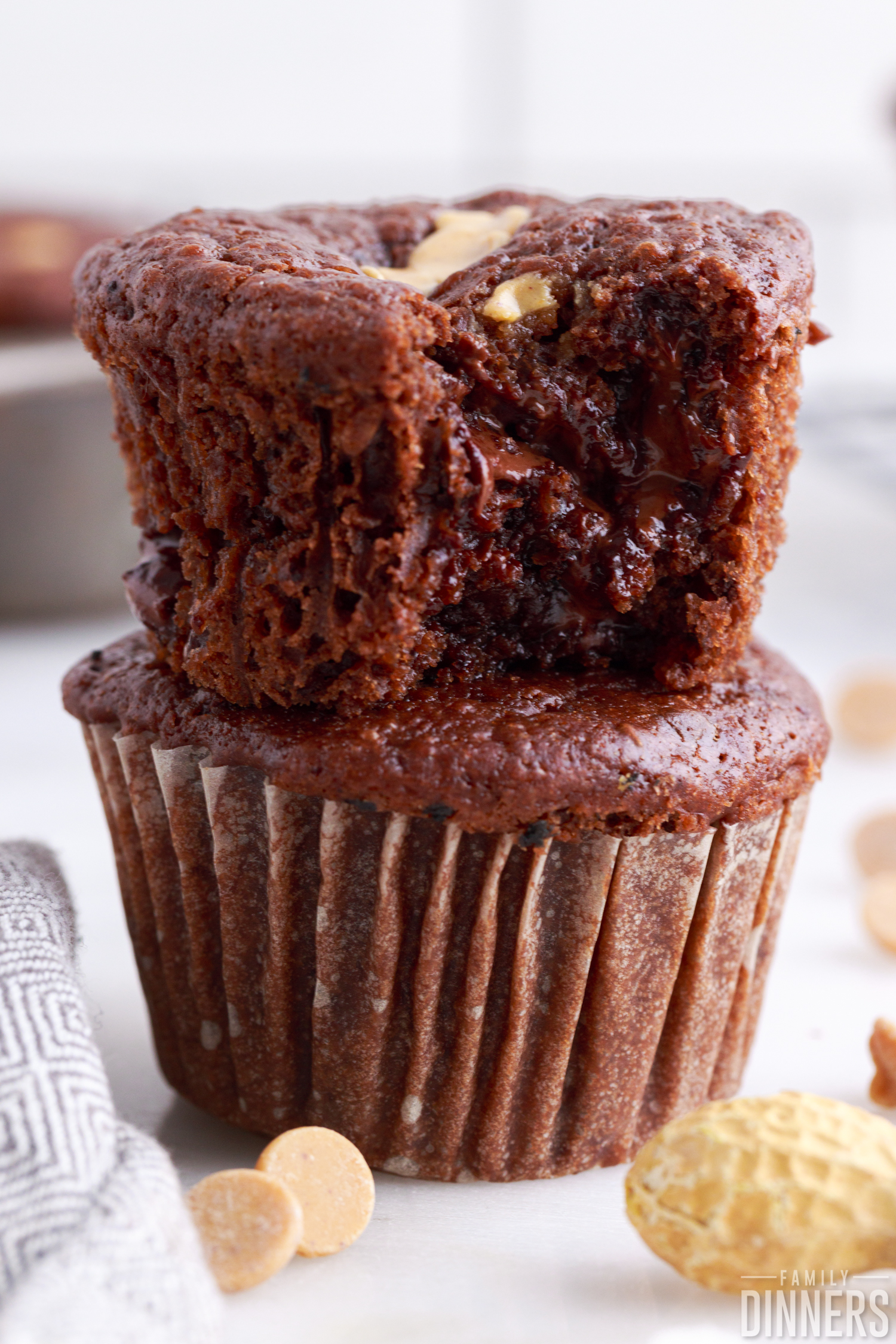 two chocolate peanut butter muffins stacked on top of each other, top one has a bite taken out of it