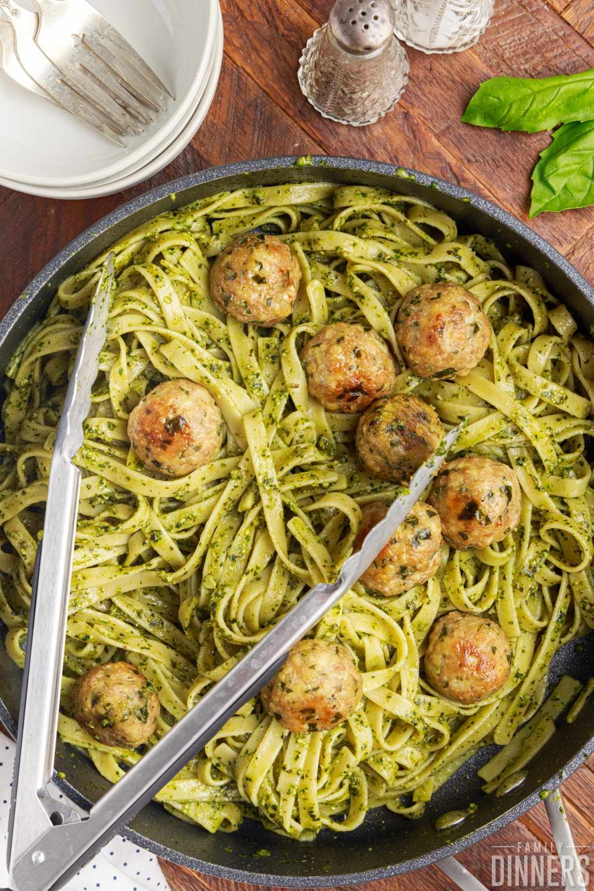 Easy basil pesto pasta with meatballs all mixed together in a large skillet.