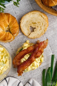 bacon on top of egg salad on an open croissant