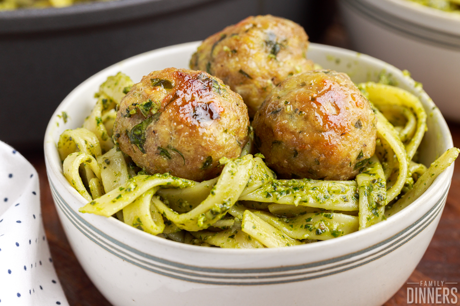 close up of a bowl full of fettuccine pesto topped with three turkey meatballs