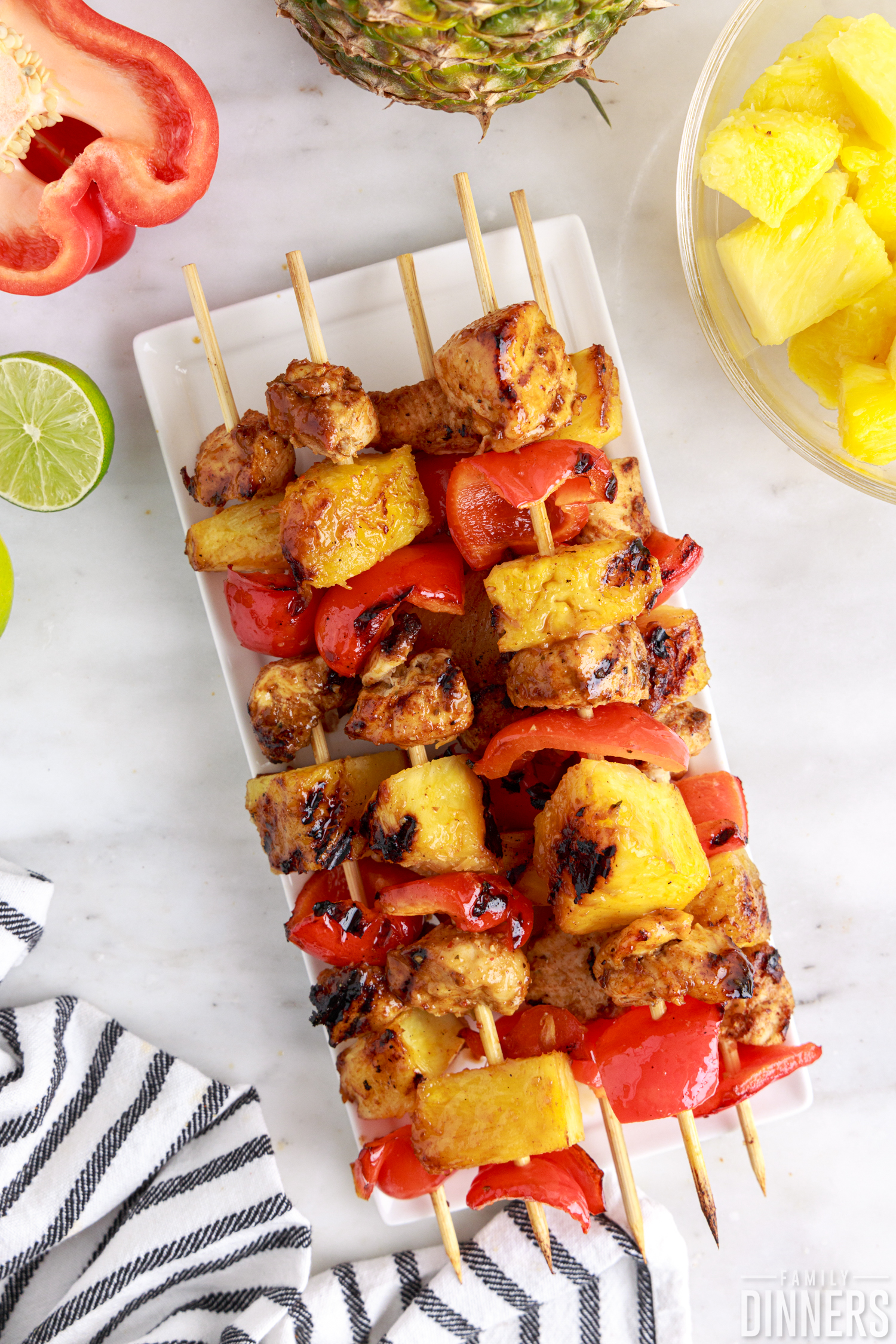 grilled chicken chipotle kabobs with peppers and pineapple on wooden skewers on white plate