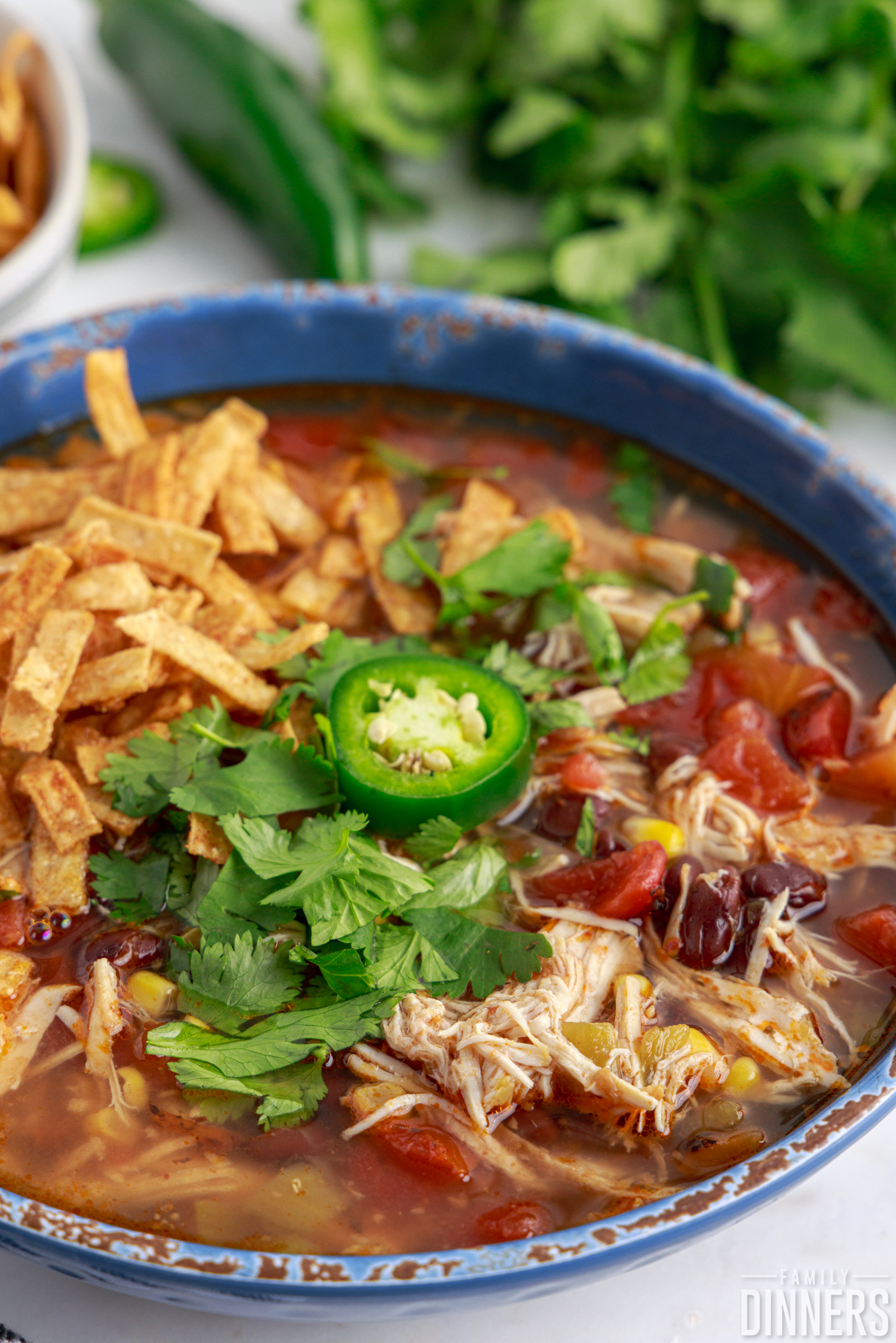 a bowl of instant pot chicken tortilla soup garnished with cilantro and a jalapeno slice