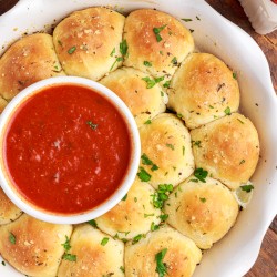 cheesy meatball stuffed biscuits in a pie dish with bowl of marinara