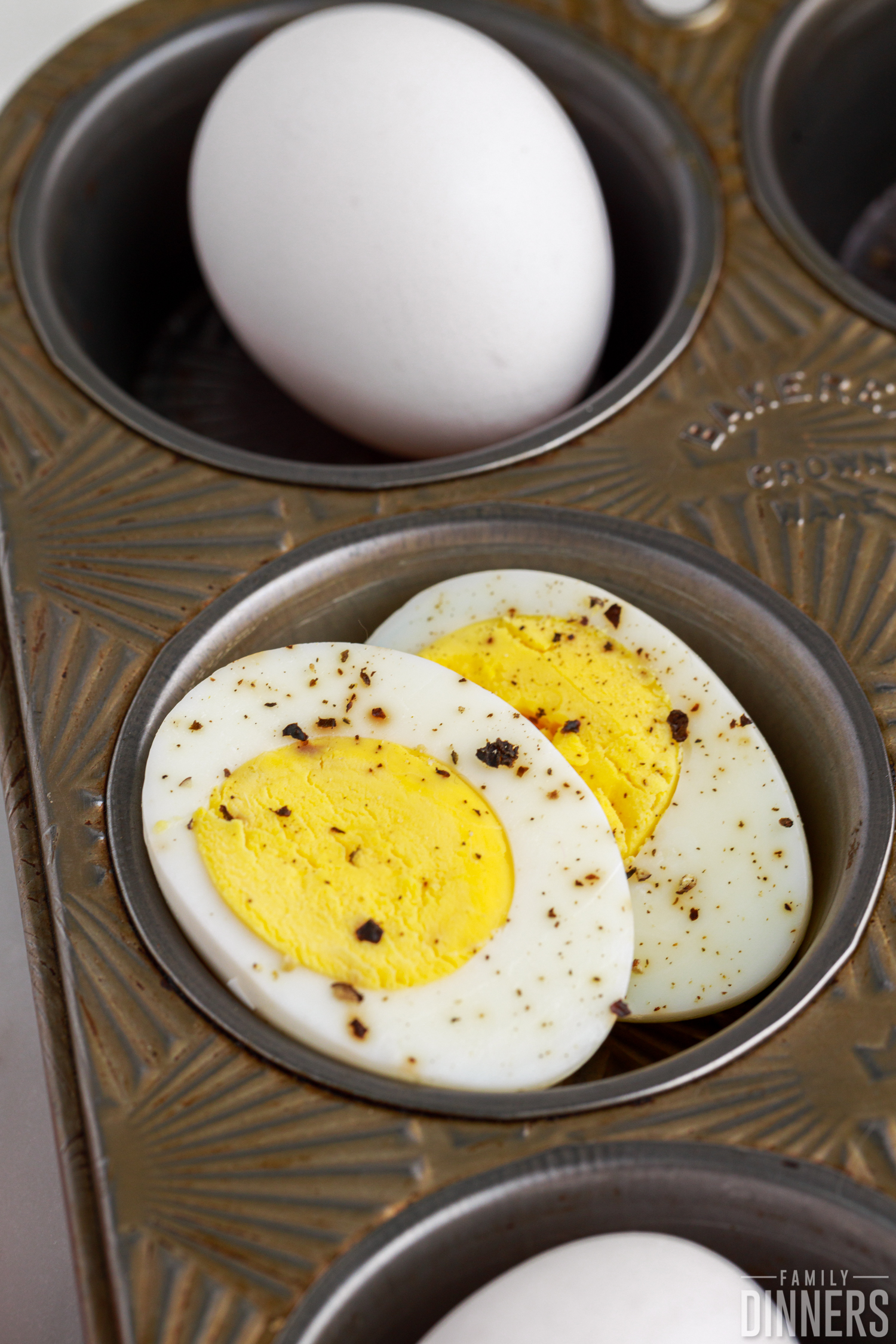 cut open hard boiled egg with salt and pepper on top inside muffin tin