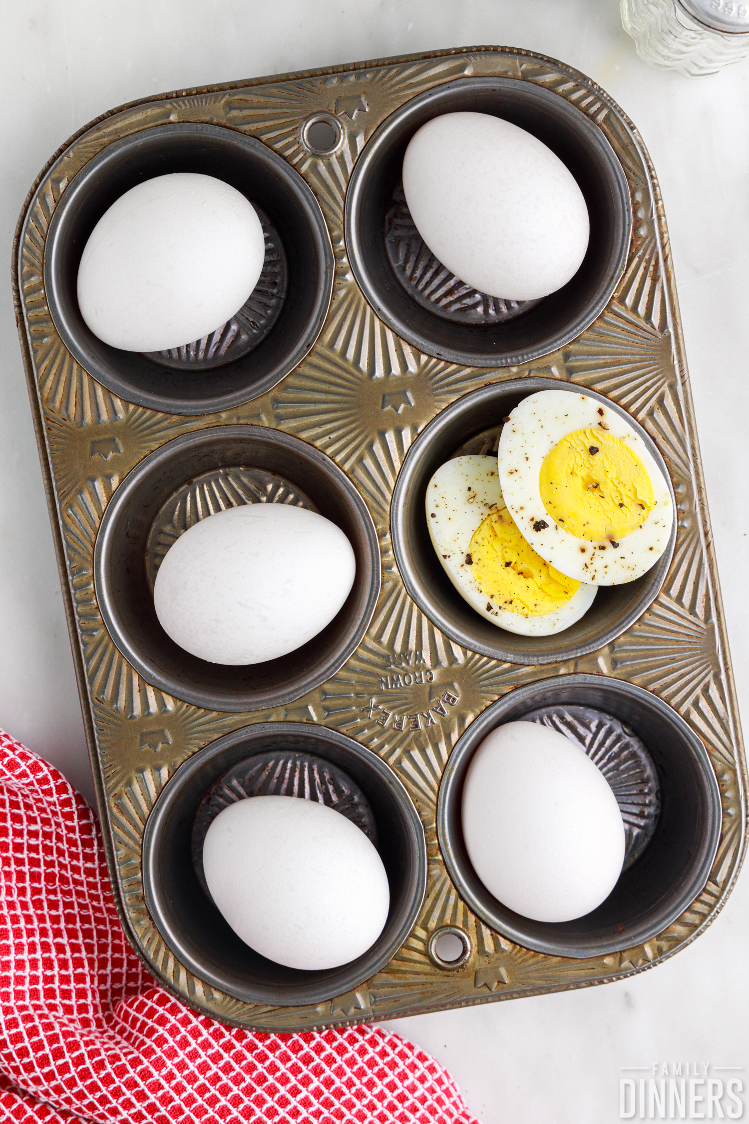 hard boiled eggs in an oven tin with one egg peeled and cut in half