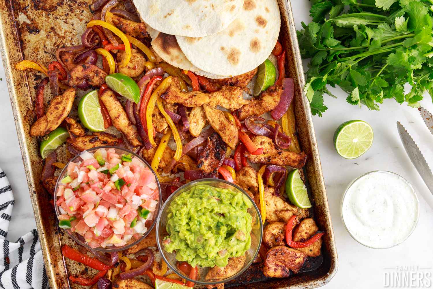 sheet pan chicken fajitas with bowls of pico, guac, and tortillas