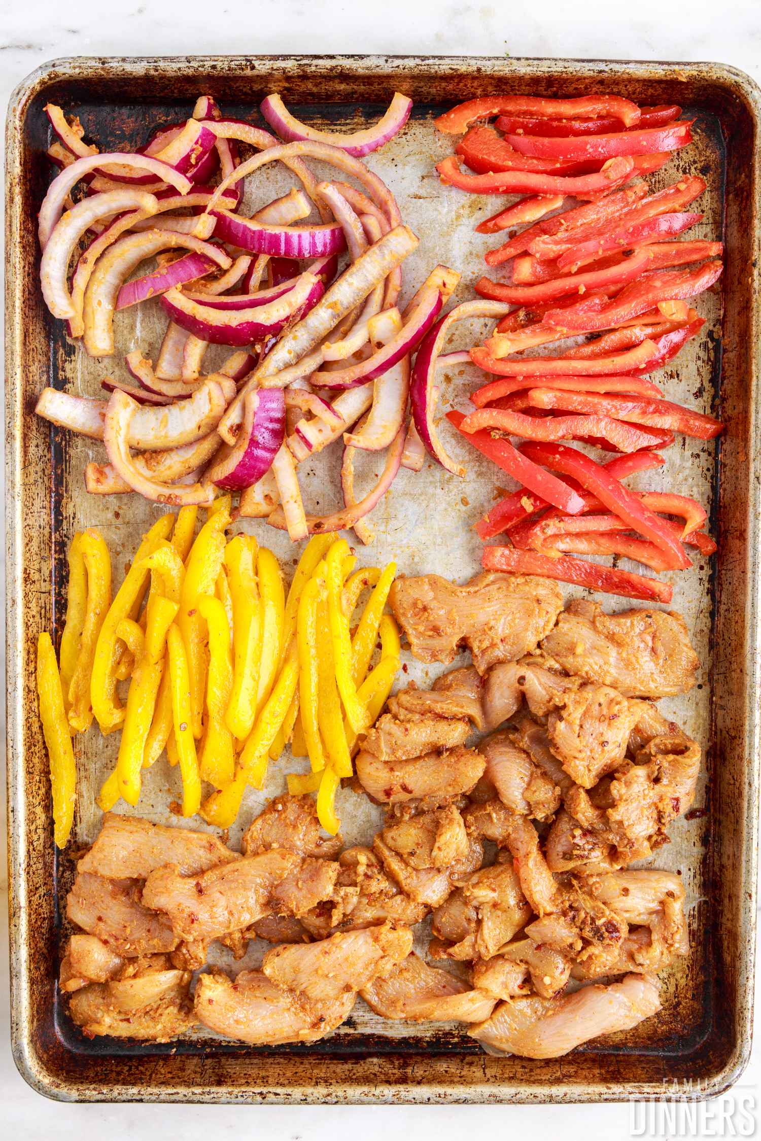 raw chicken and vegetables on a sheet pan