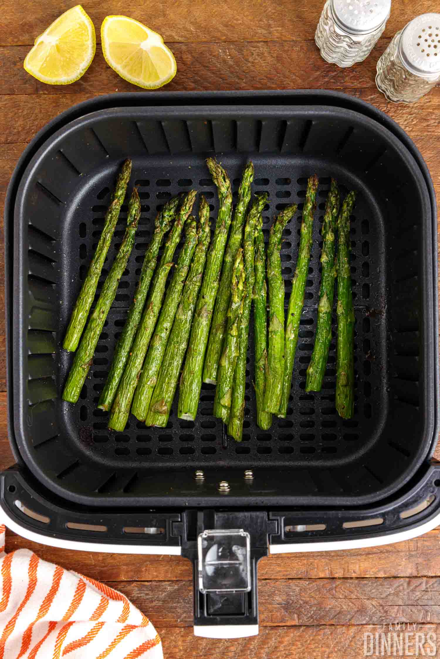 A batch of cooked asparagus stems in an air fryer basket.