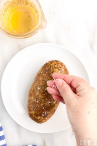 A hand sprinkling salt on potato.