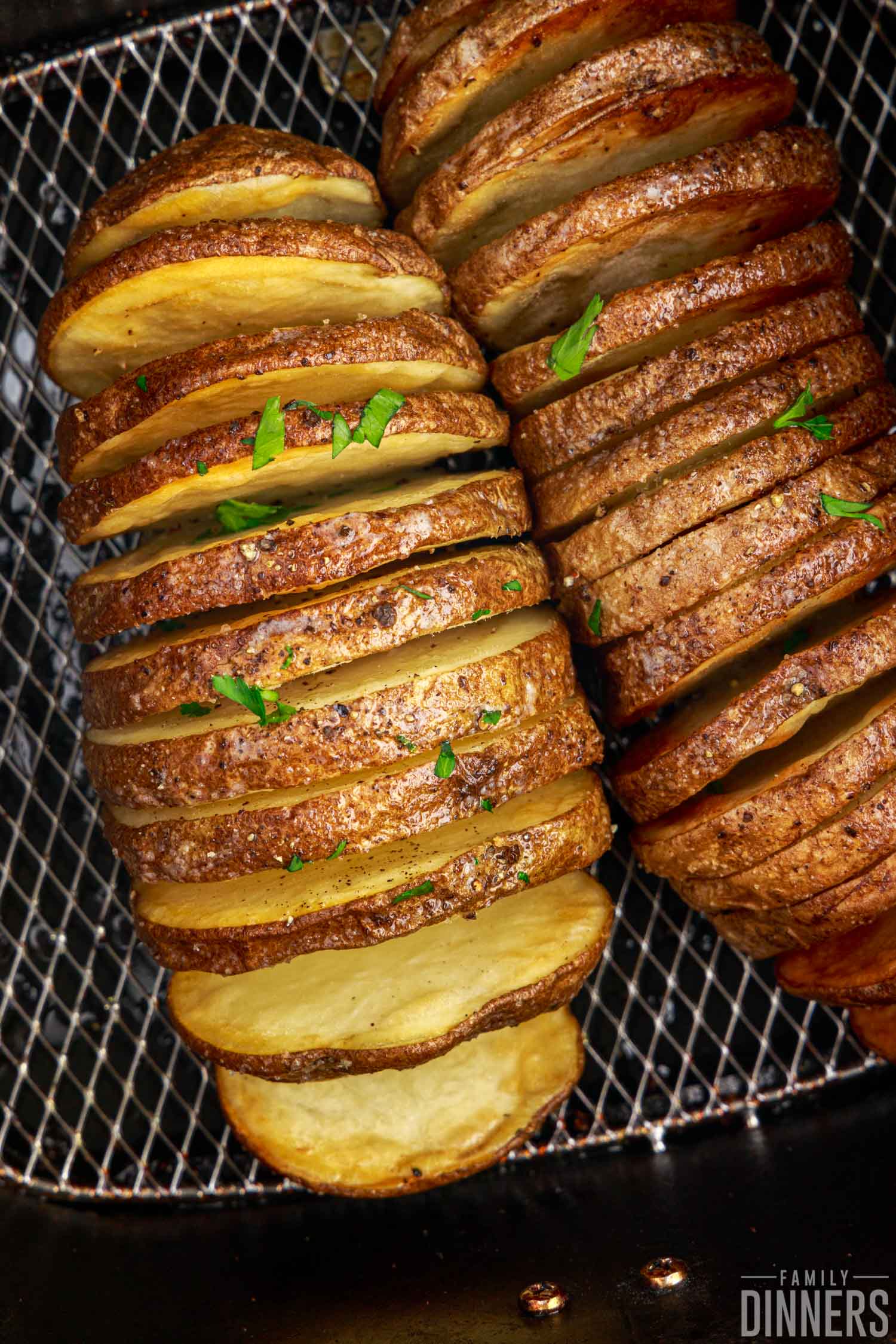 Close up of fully cooked hasselback potatoes with salt and parsley.