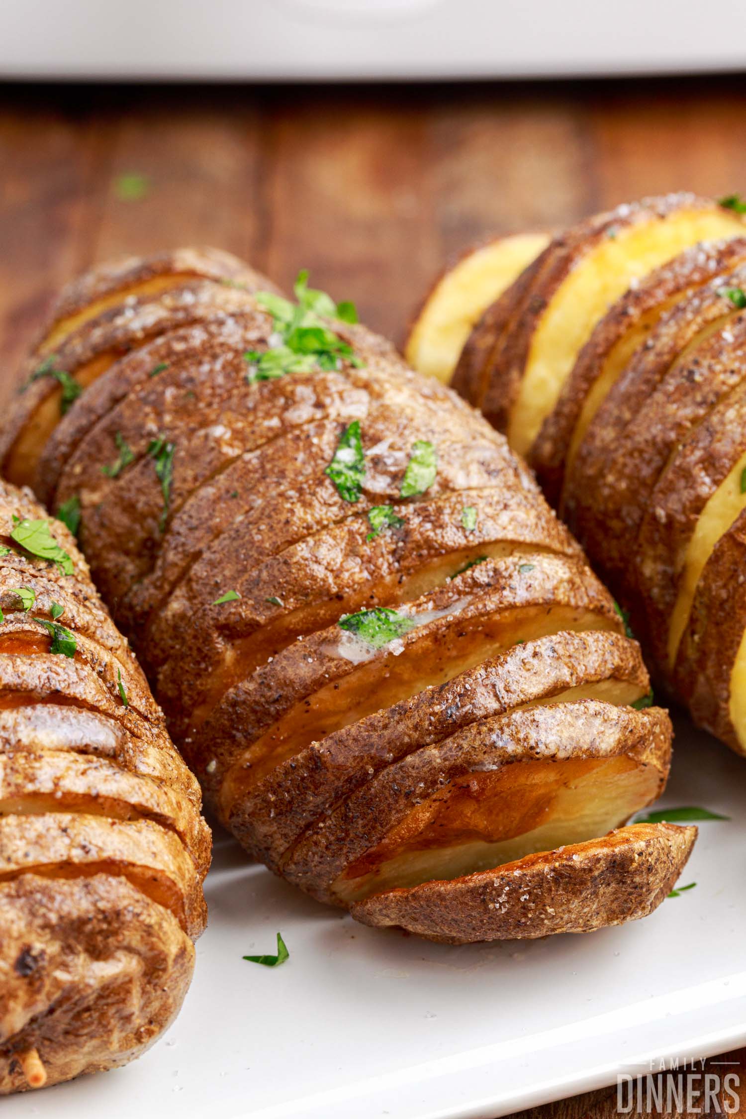 Close up of fully cooked hasselback potatoes with salt and parsley.