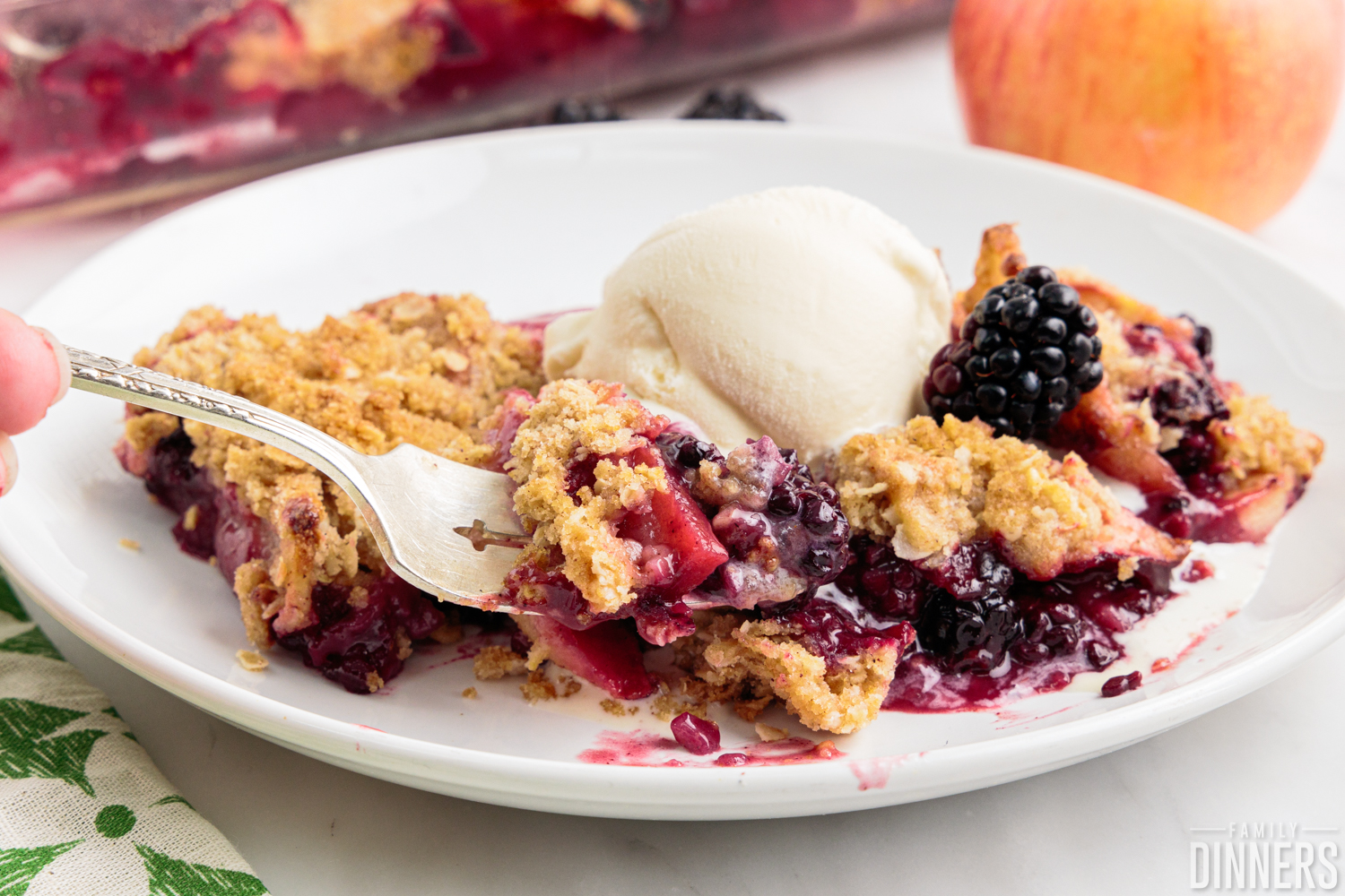 Apple blackberry crumble on a plate with ice cream.
